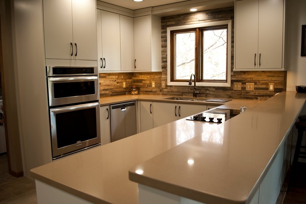 Mid-sized transitional u-shaped eat-in kitchen photo with an undermount sink, flat-panel cabinets, gray cabinets, brown backsplash, wood backsplash, stainless steel appliances and a peninsula