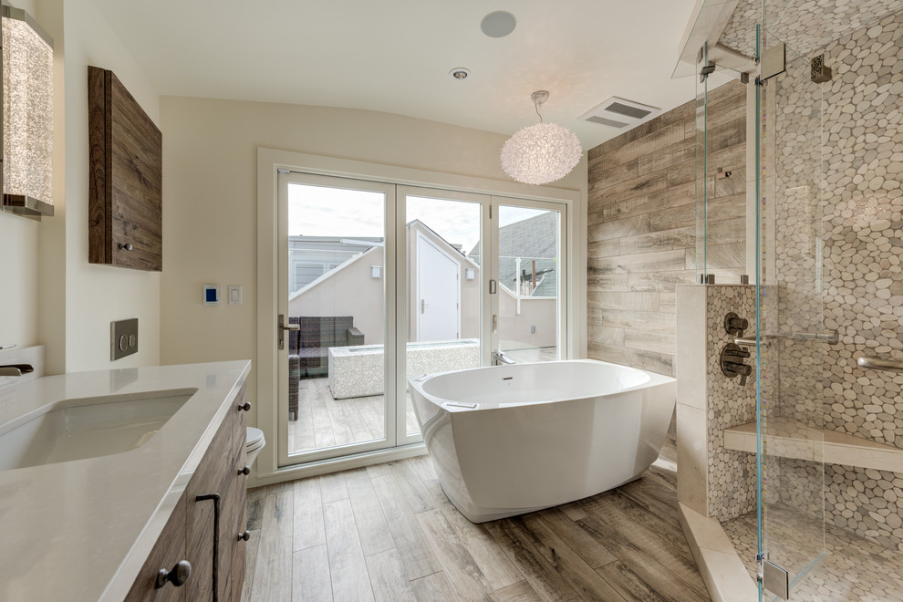 Photo of a mid-sized contemporary bathroom in San Francisco with flat-panel cabinets, a freestanding tub, a corner shower, porcelain floors, an undermount sink, brown floor, a hinged shower door, dark wood cabinets, beige tile, pebble tile and beige walls.