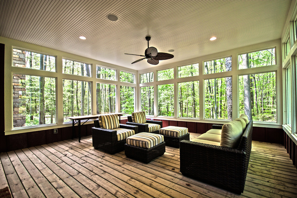 This is an example of a large traditional backyard screened-in verandah in Chicago with decking and a roof extension.