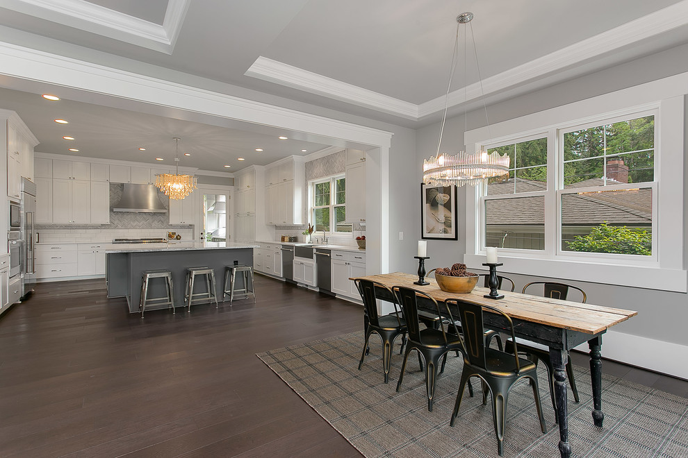 This is an example of an expansive transitional u-shaped eat-in kitchen in Seattle with a farmhouse sink, flat-panel cabinets, white cabinets, marble benchtops, multi-coloured splashback, stainless steel appliances, dark hardwood floors and with island.