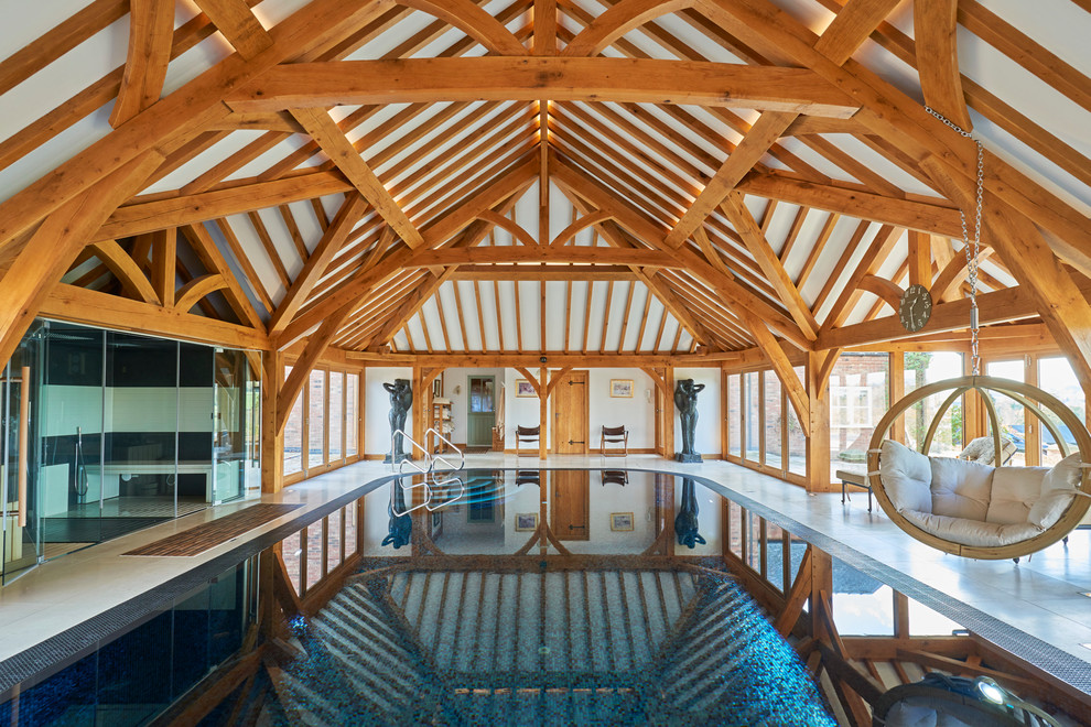 This is an example of a contemporary indoor rectangular pool in Other with a pool house.
