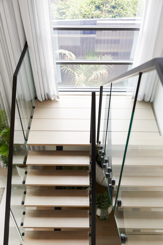 Photo of a large contemporary wood u-shaped staircase in Melbourne with open risers and metal railing.