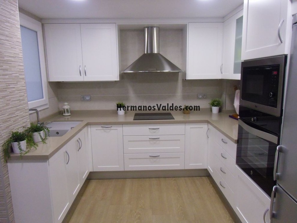 Diseño de cocinas en U tradicional renovado pequeño cerrado sin isla con electrodomésticos de acero inoxidable y suelo de madera en tonos medios