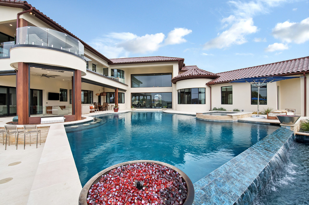 Inspiration for a mediterranean backyard custom-shaped pool in Orange County with a water feature and tile.