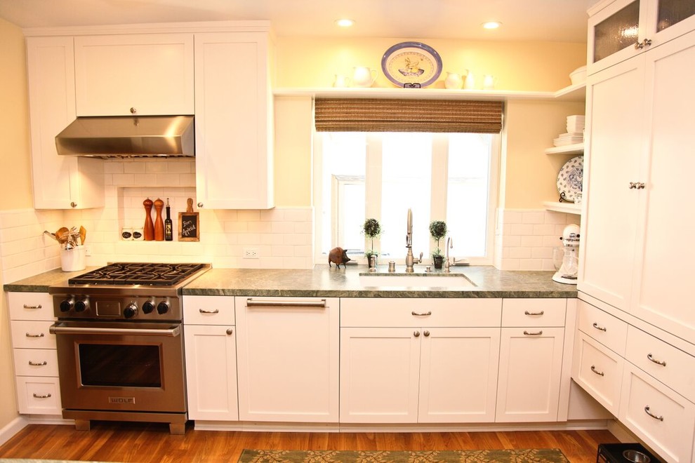 Design ideas for a mid-sized traditional galley separate kitchen in San Diego with an undermount sink, shaker cabinets, white cabinets, quartz benchtops, white splashback, subway tile splashback, panelled appliances, medium hardwood floors, no island and brown floor.
