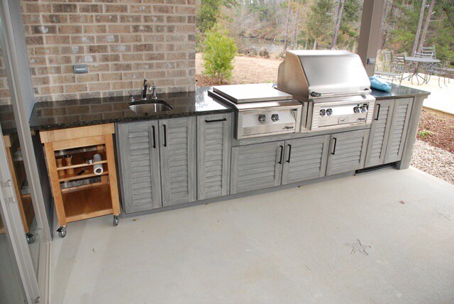 This is an example of a mid-sized modern backyard patio in Oklahoma City with an outdoor kitchen and a roof extension.