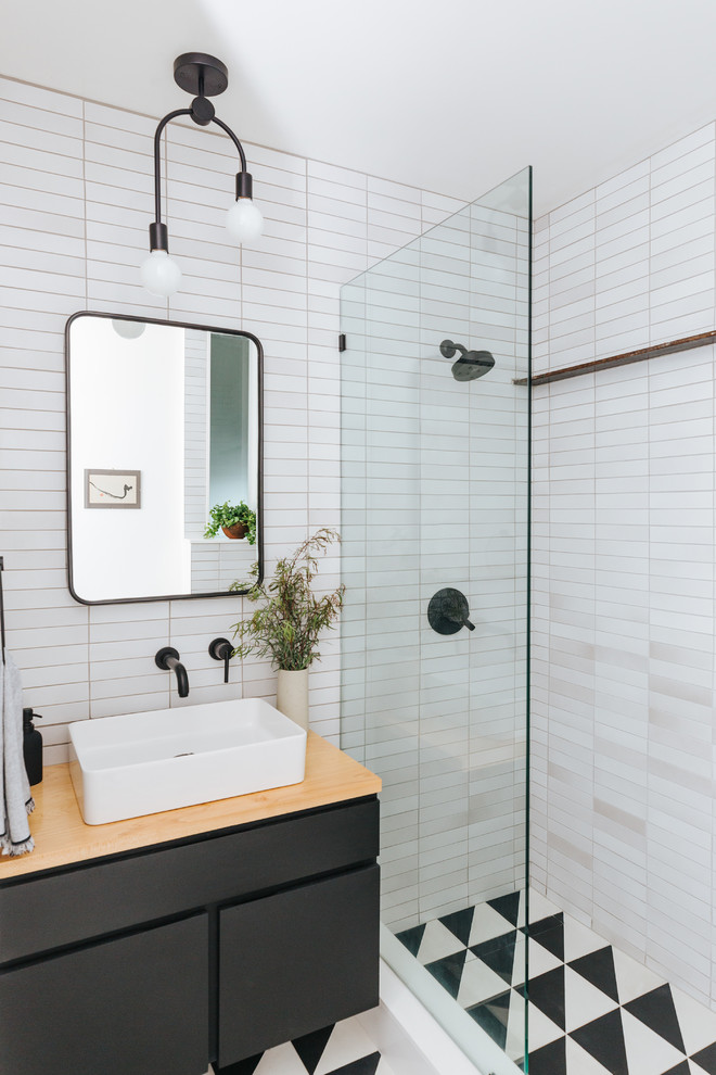 Inspiration for a scandinavian 3/4 bathroom in San Francisco with flat-panel cabinets, black cabinets, an alcove shower, white tile, white walls, a vessel sink, wood benchtops, multi-coloured floor and an open shower.