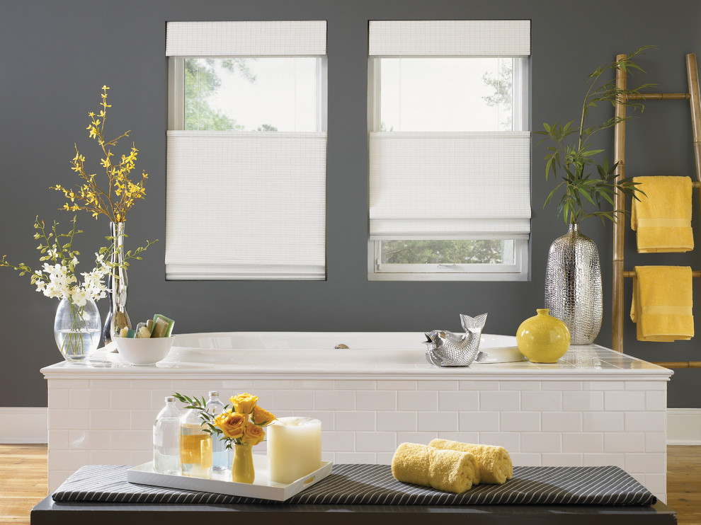 Example of a large transitional master light wood floor and beige floor drop-in bathtub design with gray walls