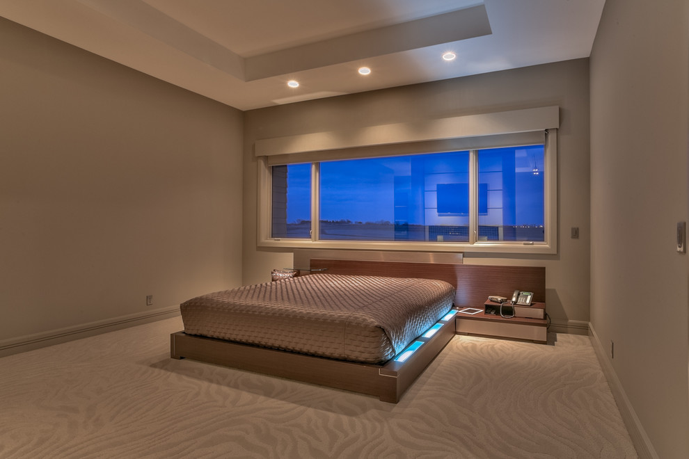 This is an example of a large contemporary master bedroom in Omaha with grey walls, carpet, a two-sided fireplace, a tile fireplace surround and beige floor.