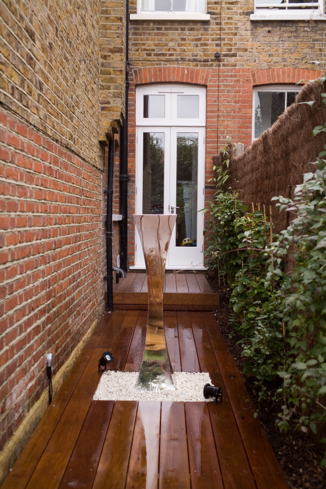 Modern backyard garden in London with with raised garden bed and a wood fence.