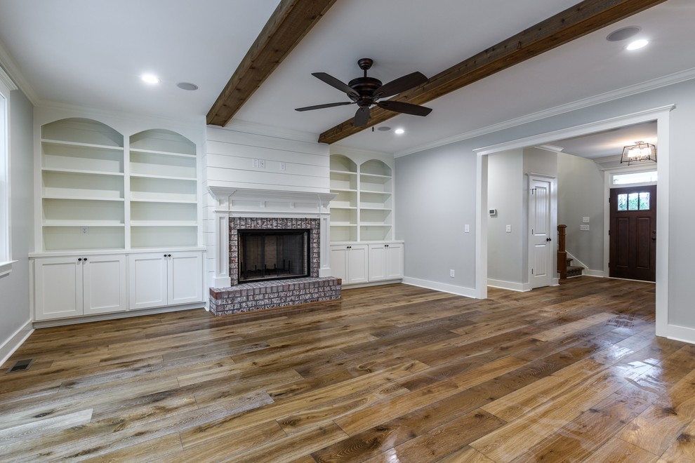 Inspiration for a mid-sized country open concept living room in Other with grey walls, medium hardwood floors, a standard fireplace, a brick fireplace surround, brown floor and no tv.