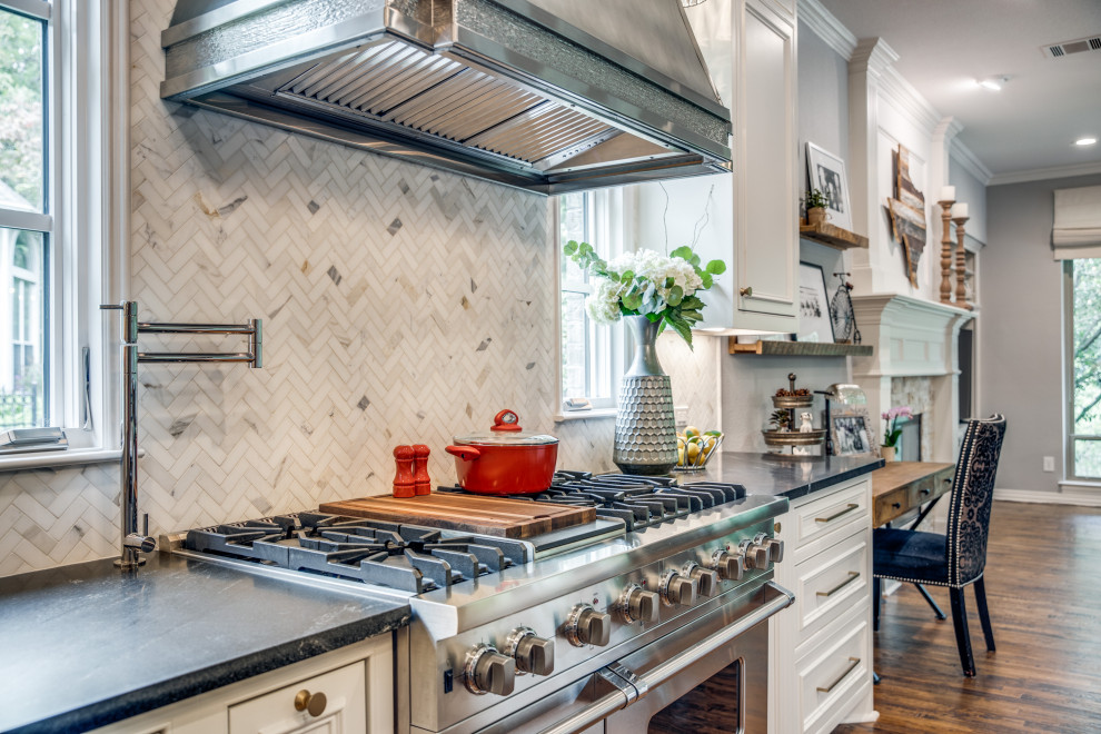 Mid-sized traditional u-shaped eat-in kitchen in Dallas with a farmhouse sink, beaded inset cabinets, white cabinets, granite benchtops, white splashback, marble splashback, stainless steel appliances, medium hardwood floors, with island and black benchtop.