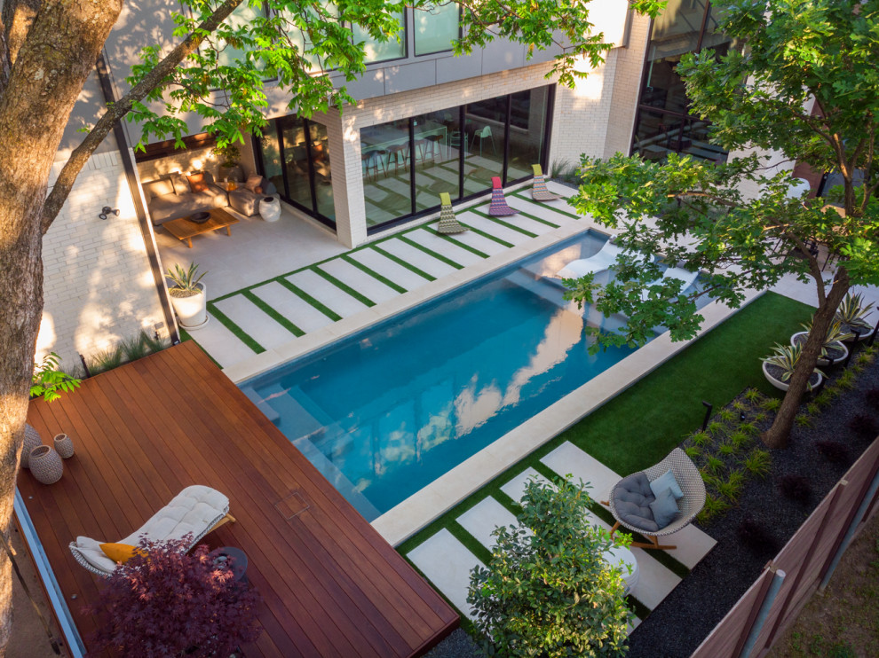 Photo of a mid-sized modern backyard rectangular pool in Dallas with natural stone pavers.