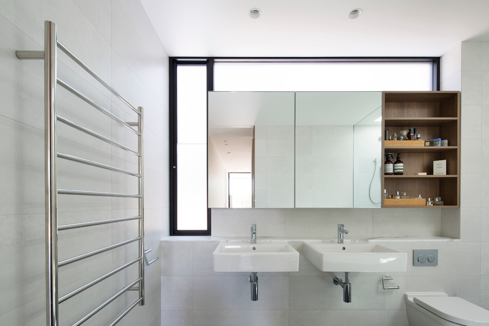 Mid-sized contemporary bathroom in Sydney with medium wood cabinets, a freestanding tub, a wall-mount toilet, white tile, ceramic tile, white walls and marble benchtops.