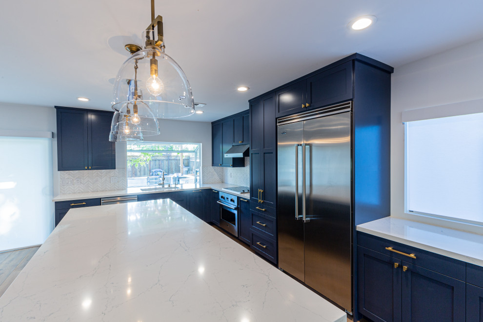 Inredning av ett modernt flerfärgad flerfärgat kök och matrum, med en undermonterad diskho, luckor med upphöjd panel, blå skåp, marmorbänkskiva, vitt stänkskydd, stänkskydd i mosaik, målat trägolv, en köksö och beiget golv