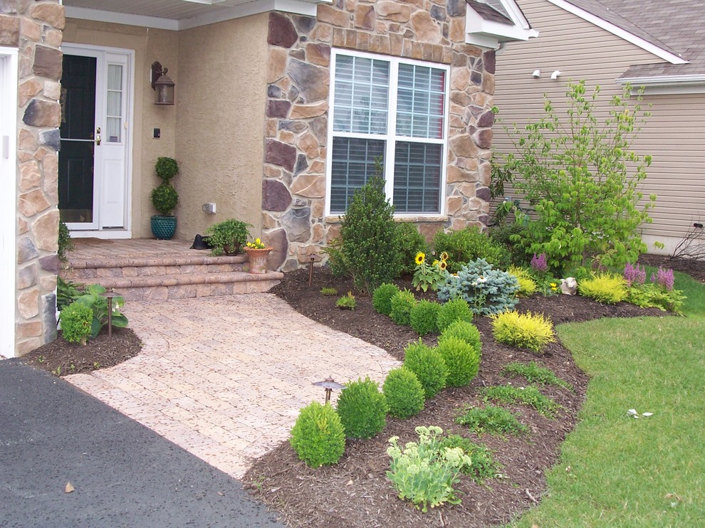 This is an example of a mid-sized traditional front yard driveway in New York with a garden path and brick pavers.