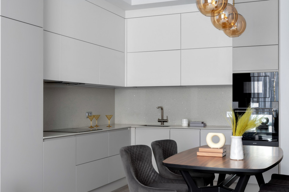 This is an example of a medium sized contemporary grey and white l-shaped kitchen/diner in Other with flat-panel cabinets, engineered stone countertops, engineered quartz splashback, black appliances, vinyl flooring, no island, a submerged sink, grey cabinets, grey splashback, brown floors and grey worktops.