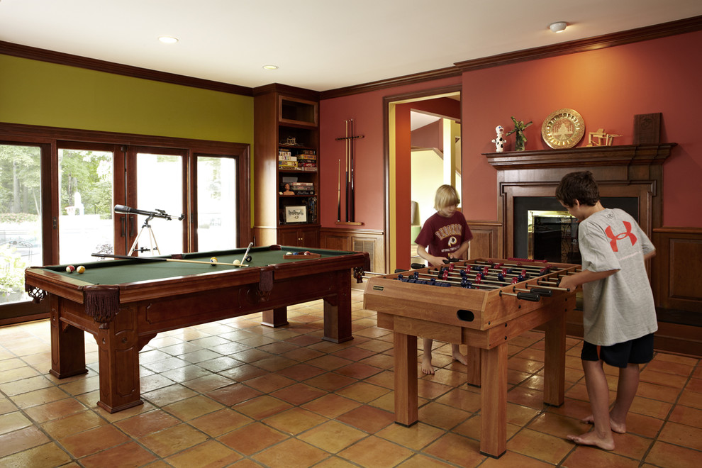 Inspiration for a mid-sized transitional walk-out basement in DC Metro with red walls, terra-cotta floors, a standard fireplace, a wood fireplace surround and orange floor.