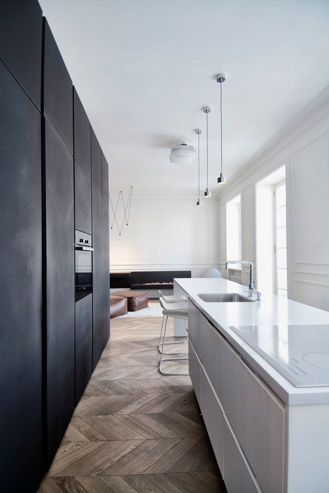 Photo of a mid-sized scandinavian single-wall eat-in kitchen in Moscow with an undermount sink, flat-panel cabinets, solid surface benchtops, black appliances, medium hardwood floors and with island.