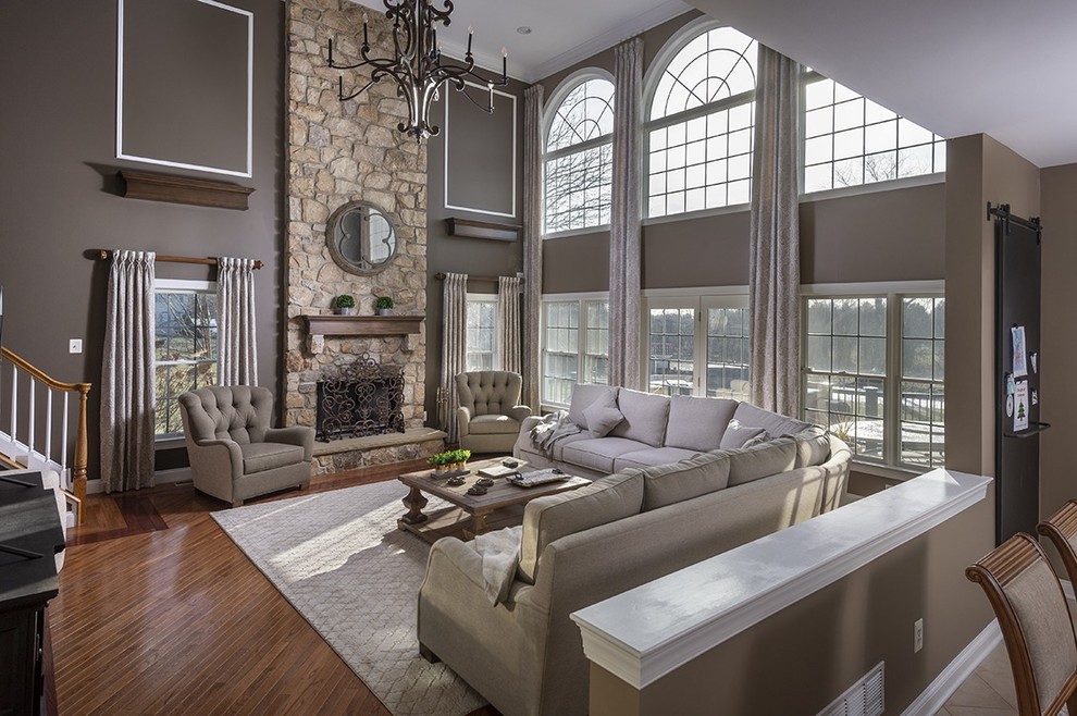 Large transitional open concept family room in Philadelphia with grey walls, medium hardwood floors, a standard fireplace, a stone fireplace surround, a freestanding tv and brown floor.