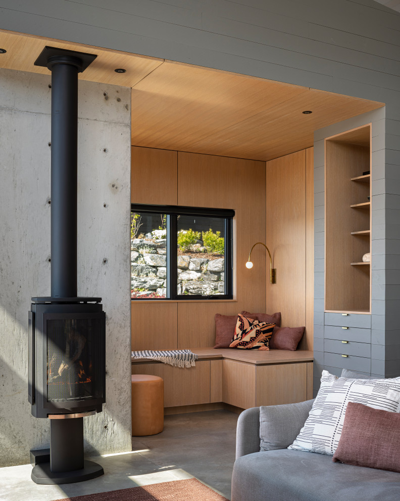 Mid-sized modern open concept living room in Other with concrete floors, a concrete fireplace surround, a library, a wood stove, no tv, grey floor, wood and wood walls.