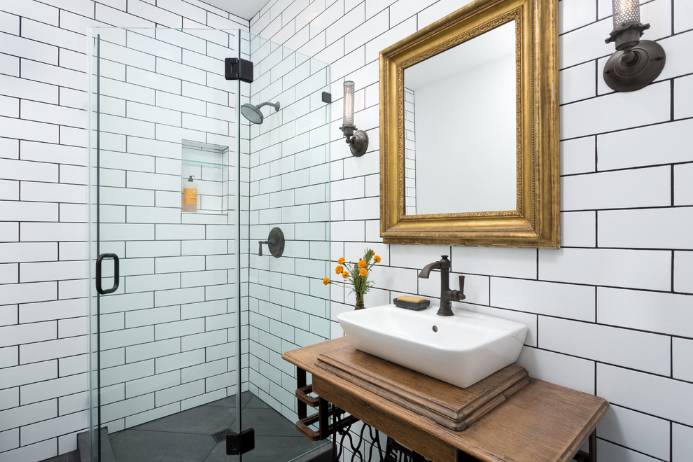 Small industrial 3/4 bathroom in Los Angeles with furniture-like cabinets, medium wood cabinets, a corner shower, a two-piece toilet, white tile, ceramic tile, white walls, porcelain floors, a vessel sink, wood benchtops, black floor and a hinged shower door.