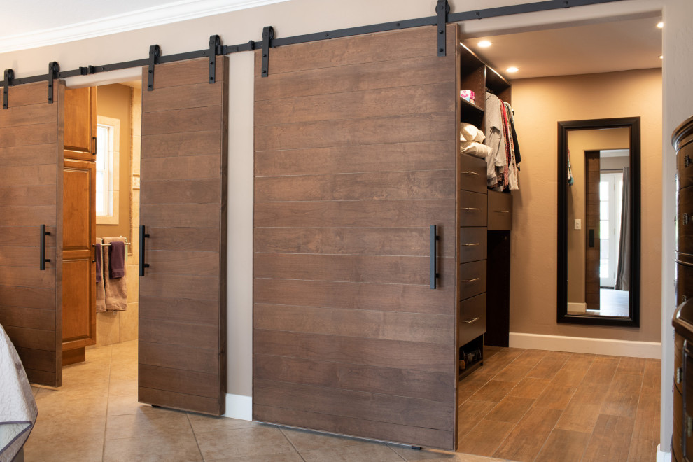 Ejemplo de armario vestidor unisex moderno grande con armarios con paneles lisos, puertas de armario de madera en tonos medios, suelo laminado y suelo marrón
