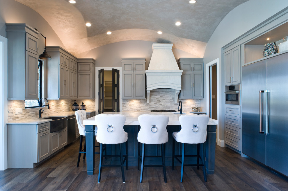 Example of a mid-sized transitional u-shaped medium tone wood floor and brown floor eat-in kitchen design with a farmhouse sink, raised-panel cabinets, gray cabinets, marble countertops, multicolored backsplash, mosaic tile backsplash, stainless steel appliances and an island