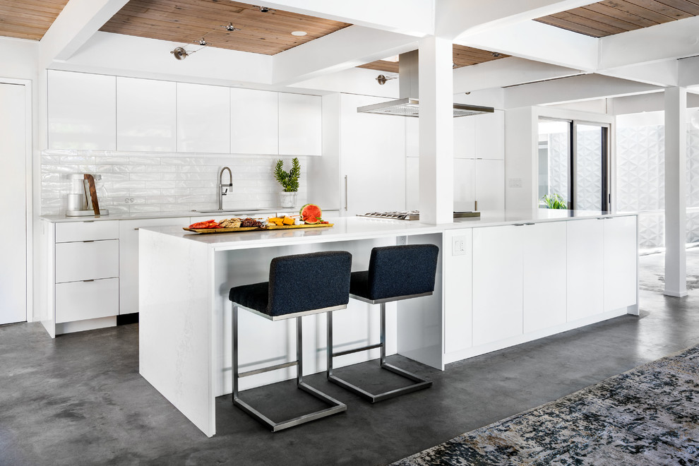 Design ideas for a small midcentury galley eat-in kitchen in Portland with a single-bowl sink, flat-panel cabinets, white cabinets, quartz benchtops, white splashback, ceramic splashback, panelled appliances, concrete floors, with island and grey floor.