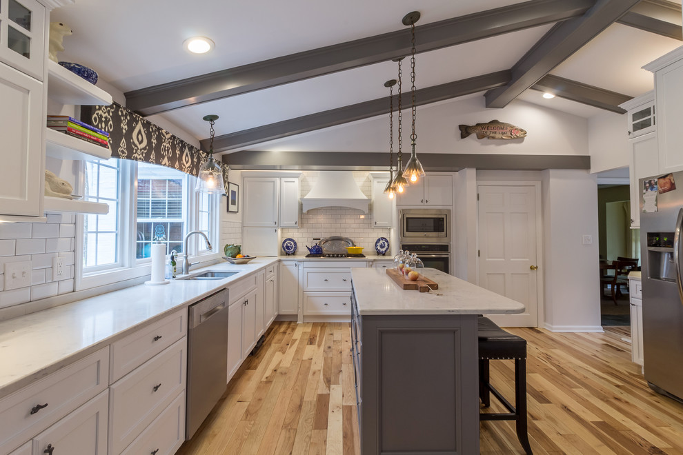 Enclosed kitchen - large transitional u-shaped medium tone wood floor and brown floor enclosed kitchen idea with an undermount sink, shaker cabinets, white cabinets, quartzite countertops, white backsplash, subway tile backsplash, stainless steel appliances and an island