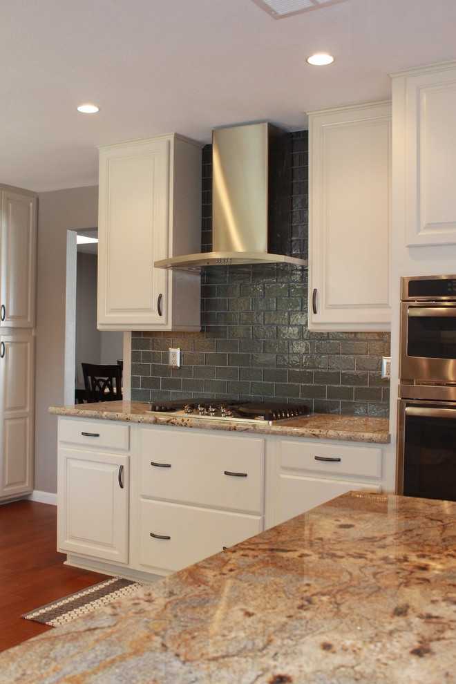 Eat-in kitchen - mid-sized transitional u-shaped dark wood floor and brown floor eat-in kitchen idea in Phoenix with an undermount sink, raised-panel cabinets, white cabinets, granite countertops, green backsplash, glass tile backsplash, stainless steel appliances and a peninsula