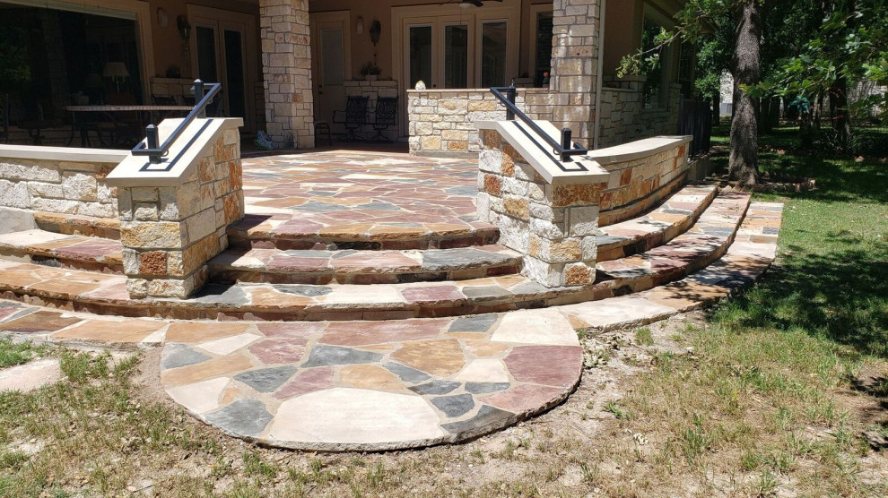 Expansive country backyard patio in Austin with natural stone pavers.