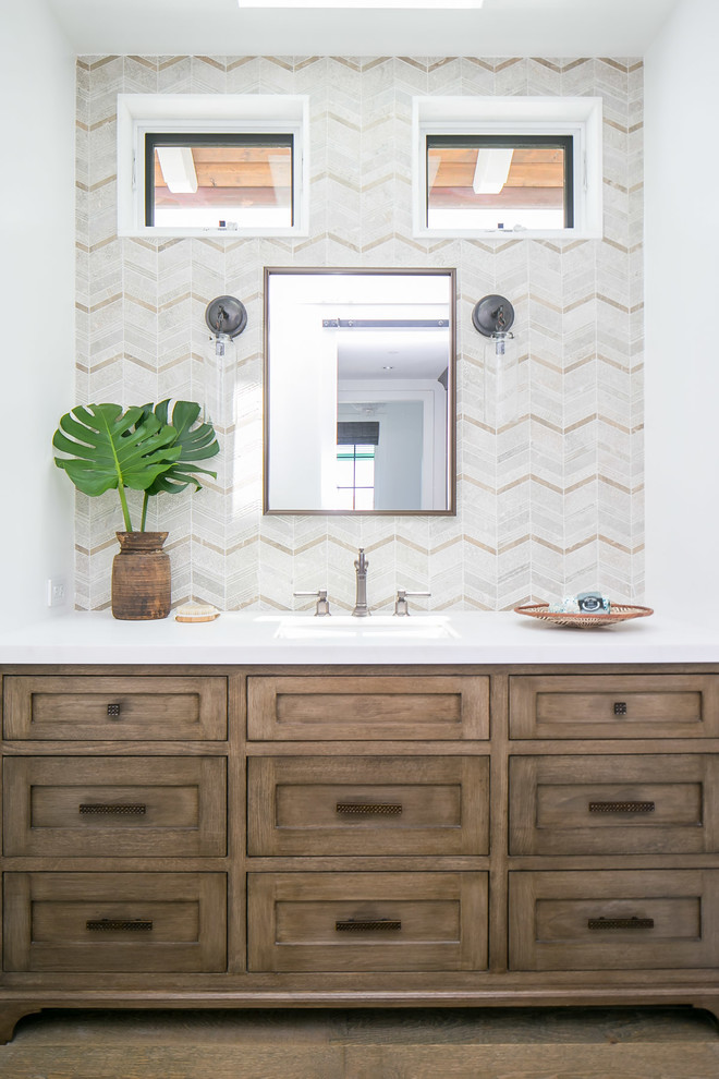 Design ideas for a tropical bathroom in Orange County with shaker cabinets, medium wood cabinets, beige tile, mosaic tile, white walls, an undermount sink, brown floor and white benchtops.
