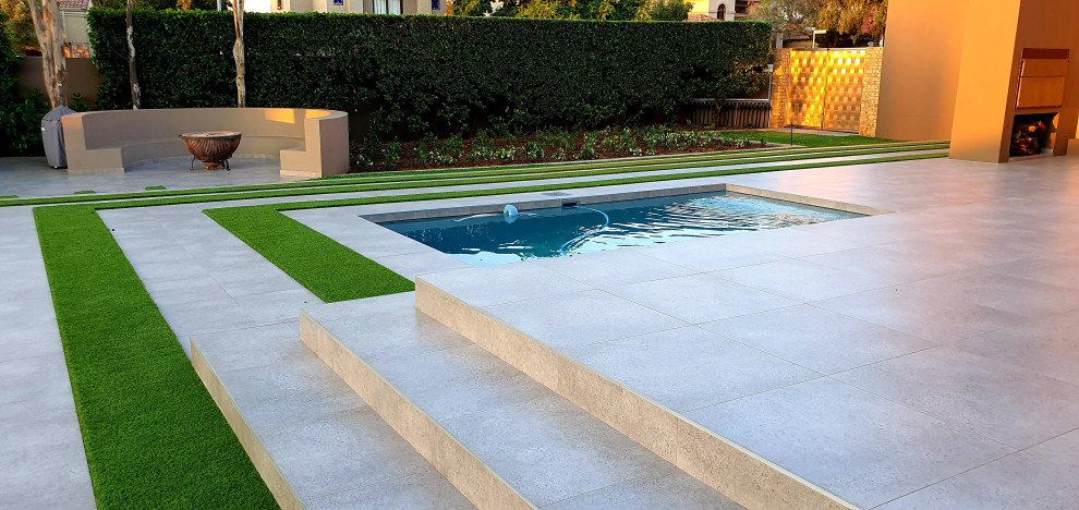 Foto di una grande piscina moderna rettangolare dietro casa con paesaggistica bordo piscina e piastrelle