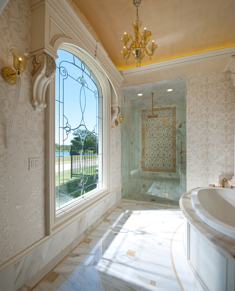 This is an example of an expansive traditional master bathroom in Dallas with a drop-in tub, an alcove shower, beige tile, marble, multi-coloured walls, marble floors, marble benchtops, multi-coloured floor and a hinged shower door.