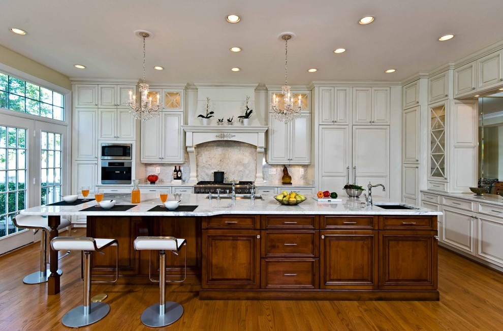 Inspiration for a large traditional l-shaped open plan kitchen in DC Metro with an undermount sink, white cabinets, white splashback, panelled appliances, recessed-panel cabinets, marble benchtops, stone slab splashback, medium hardwood floors and with island.