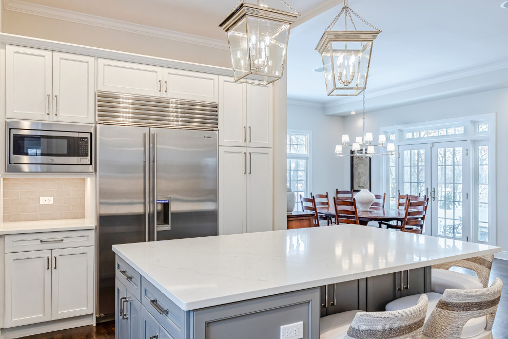 Large transitional u-shaped dark wood floor and brown floor eat-in kitchen photo in Chicago with a farmhouse sink, beaded inset cabinets, white cabinets, quartz countertops, gray backsplash, glass tile backsplash, stainless steel appliances, an island and white countertops