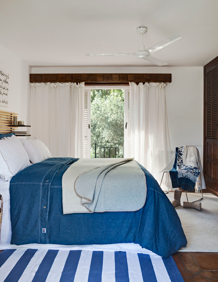 This is an example of a mid-sized beach style master bedroom in Other with white walls, terra-cotta floors and no fireplace.