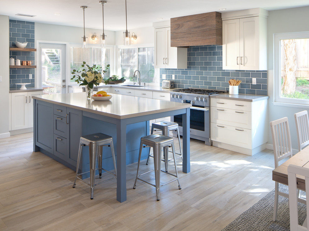 Large beach style u-shaped kitchen in San Diego with an undermount sink, shaker cabinets, blue cabinets, quartz benchtops, blue splashback, porcelain splashback, stainless steel appliances, porcelain floors, with island, beige floor and grey benchtop.