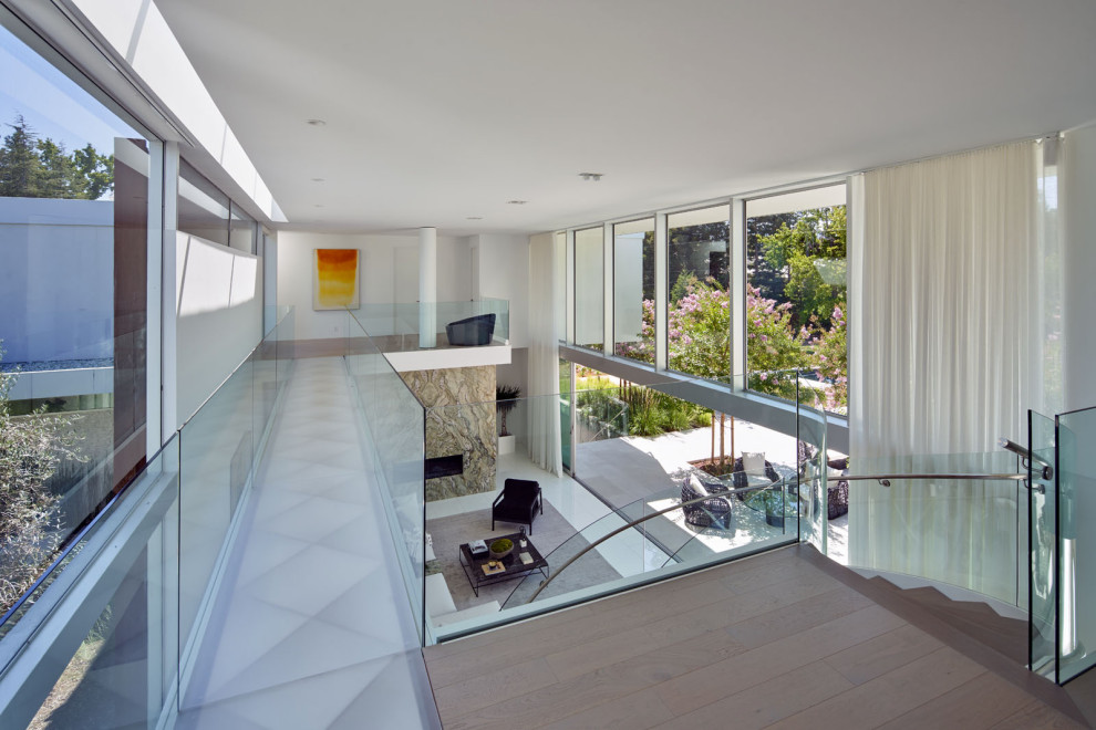 Inspiration for a large contemporary wood curved glass railing staircase in San Francisco with wood risers.