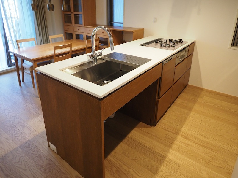 Photo of a small modern galley open plan kitchen in Tokyo with a submerged sink, flat-panel cabinets, brown cabinets, engineered stone countertops, white appliances, plywood flooring, a breakfast bar, brown floors, white worktops and a wood ceiling.