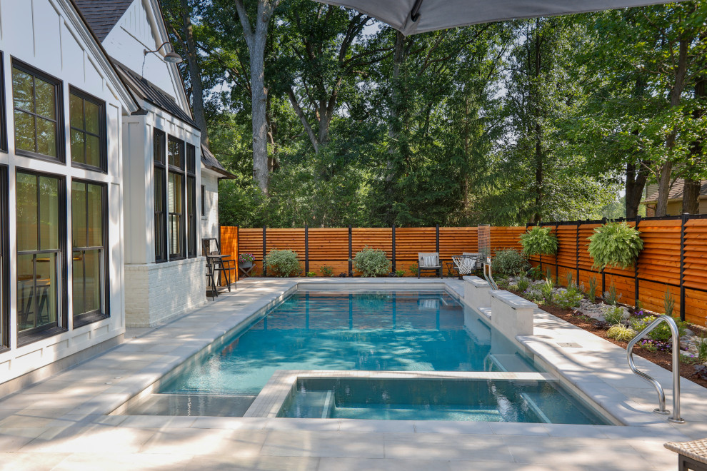 Foto de piscina alargada tradicional de tamaño medio rectangular en patio trasero con privacidad y adoquines de piedra natural