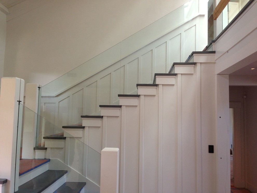 This is an example of a mid-sized beach style wood l-shaped staircase in San Francisco with wood risers and glass railing.
