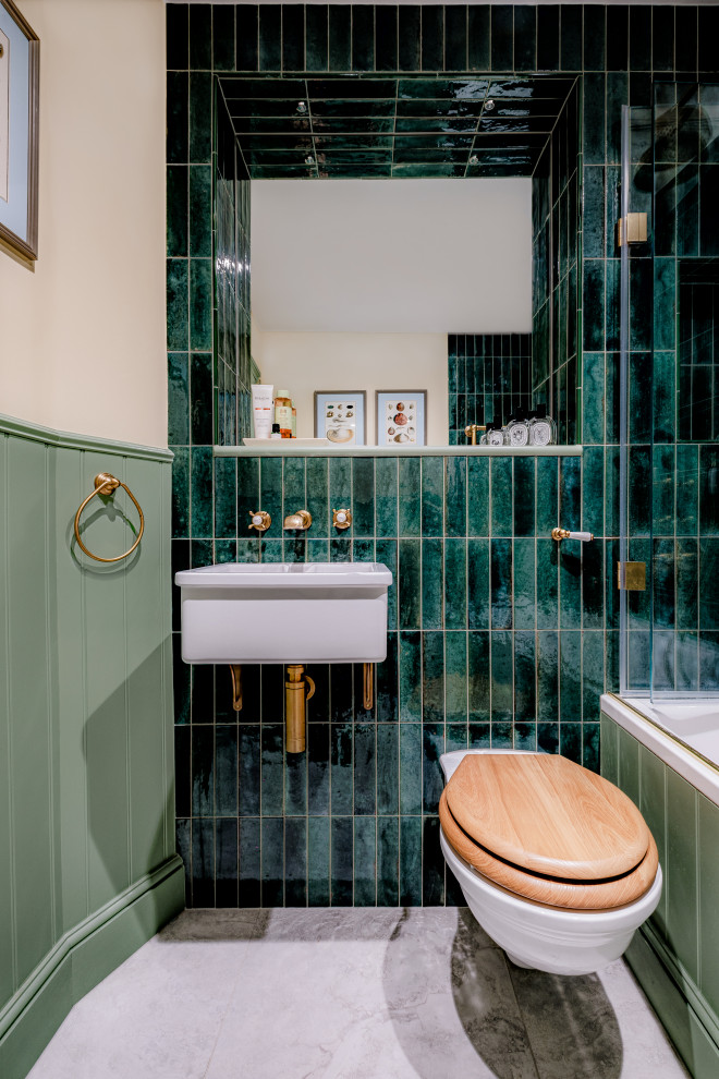 На фото: ванная комната среднего размера в классическом стиле с ванной в нише, душем над ванной, инсталляцией, зеленой плиткой, керамической плиткой, белыми стенами, полом из керамогранита, подвесной раковиной, серым полом, тумбой под одну раковину и панелями на части стены