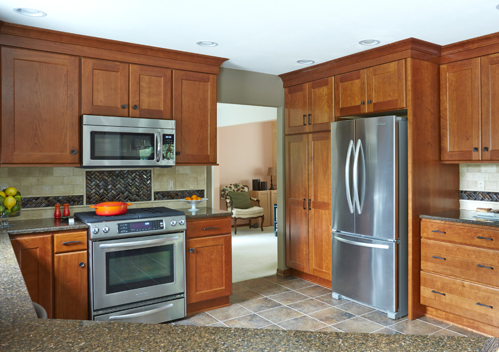 Photo of a medium sized classic l-shaped enclosed kitchen in Milwaukee with a submerged sink, shaker cabinets, medium wood cabinets, engineered stone countertops, beige splashback, stone tiled splashback, stainless steel appliances and a breakfast bar.
