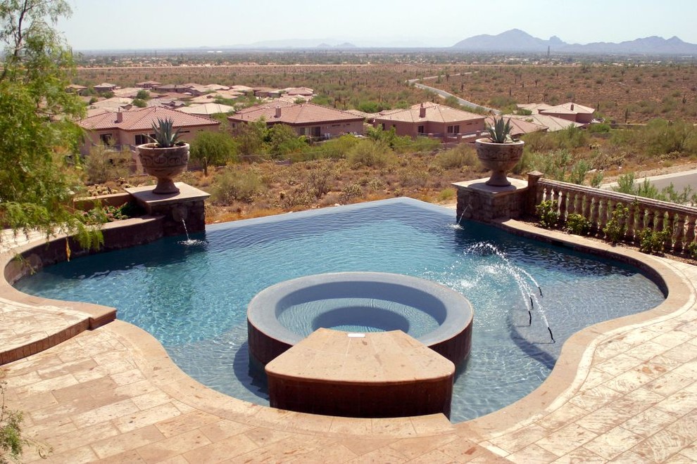 Example of a large backyard stone and custom-shaped infinity hot tub design in Phoenix