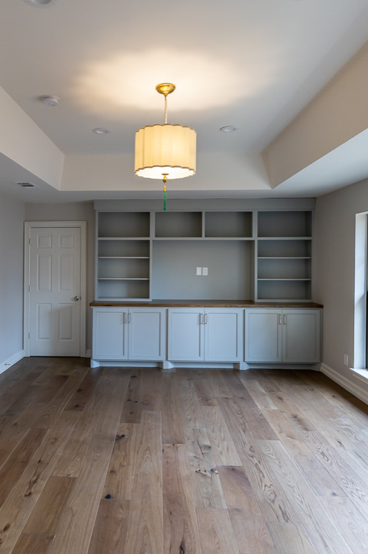 Diseño de sala de estar con biblioteca clásica renovada de tamaño medio con paredes grises, suelo de madera en tonos medios y pared multimedia