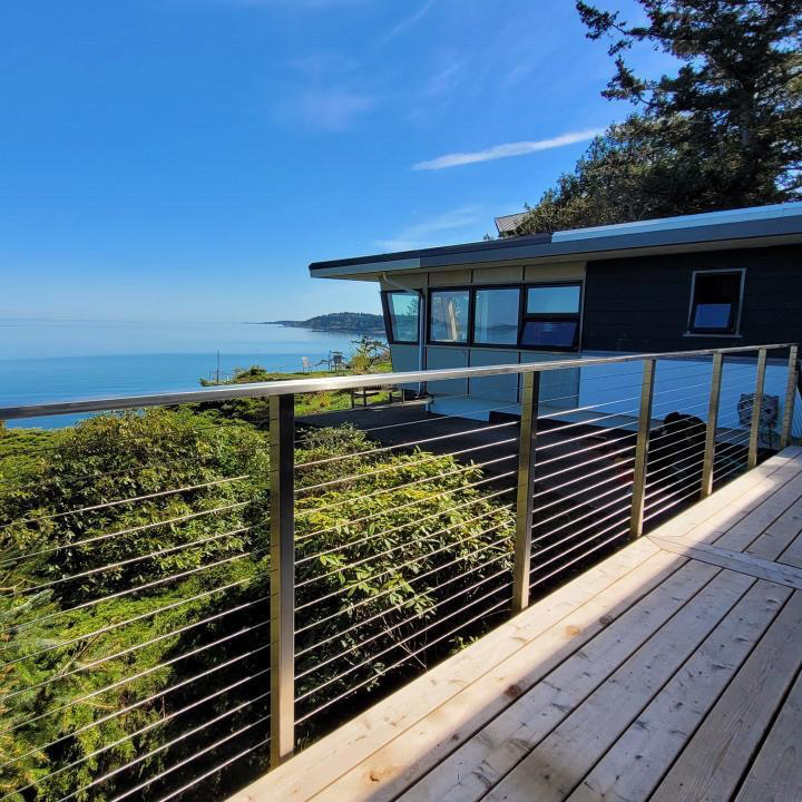 This is an example of a beach style backyard and first floor deck in Vancouver with cable railing.
