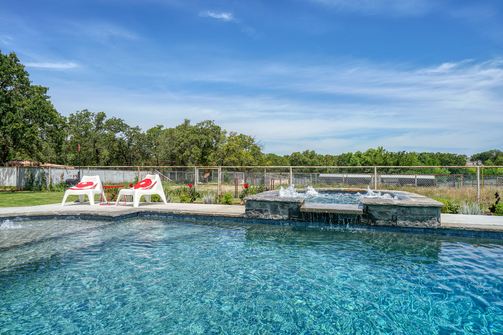 Photo of a mid-sized traditional backyard custom-shaped pool in Dallas with a hot tub and concrete slab.