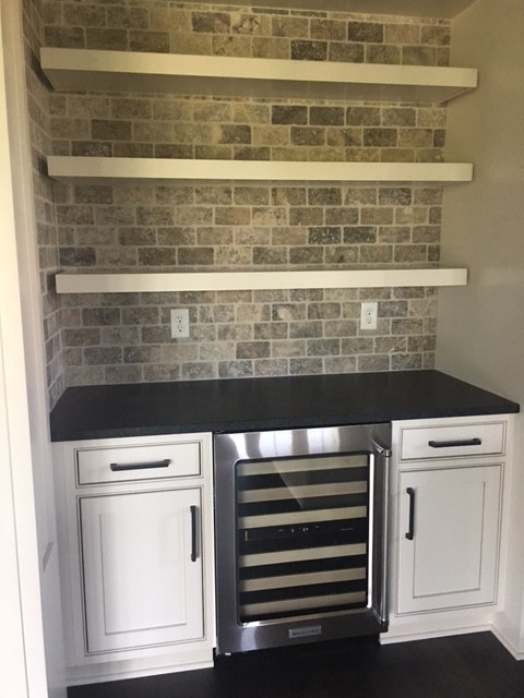 Small single-wall wet bar in Columbus with beaded inset cabinets, white cabinets, solid surface benchtops, brown splashback and stone tile splashback.